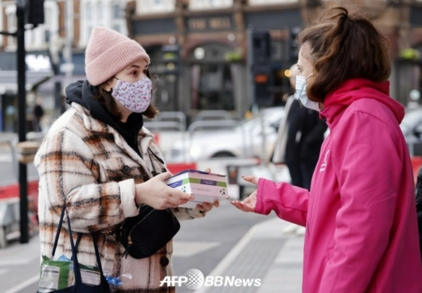 자원봉사자들이 2022년 지난달 3일 런던 북동부에서 Covid-19 신속항원검사(LFT) 박스를 나눠주고 있다. ⓒAFPBBNews