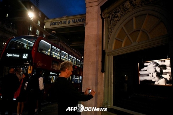 영국 런던 중심부의 포트남 앤 메이슨 본점 앞에서 엘리자베스 여왕을 추모하는 쇼윈도의 사진을 촬영하는 사람(2022년 9월 15일 촬영). ⓒAFPBBNews